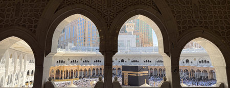 Pilgrims performing tawaf around the Kaaba seen through ornate mosque arches at Masjid al-Haram in Meccaの写真素材