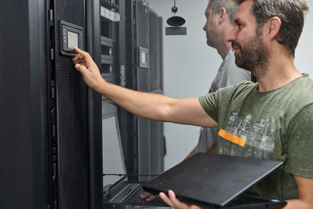 It technician checking server rack control panel in data center with laptop