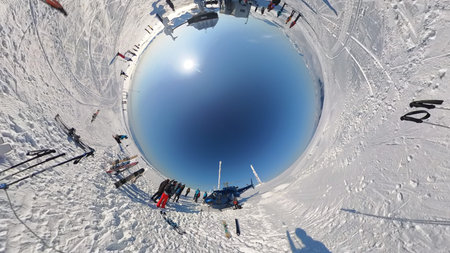 Tiny Planet of Helicopter Landing on Snow at Alpine Ski Resort Summit