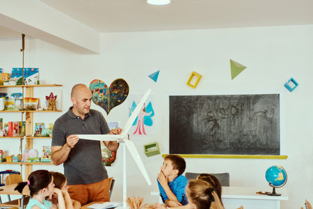 Teacher demonstrating a model wind turbine to elementary students during a hands-on classroom...