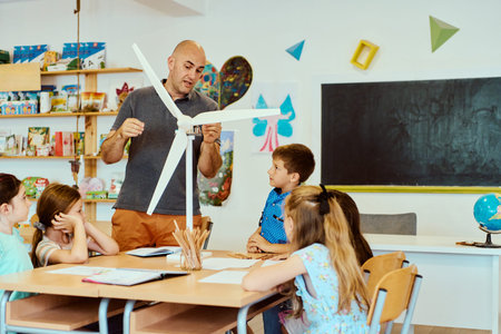 Teacher demonstrating a wind turbine model to elementary students during a hands-on STEM classroom...