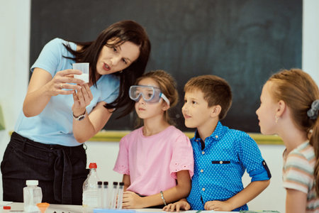 Teacher conducting a hands-on science experiment with attentive elementary students in classroomの写真素材