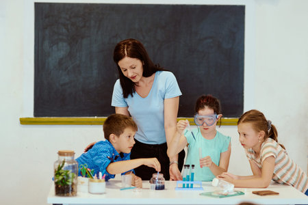 Teacher guides children through a hands-on science experiment in classroom with test tubes and...
