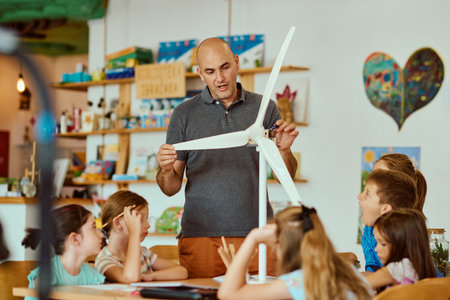 Teacher demonstrating a model wind turbine to children in a hands-on STEM classroom lesson on...