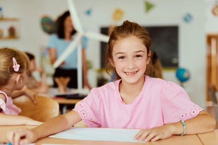Smiling schoolgirl at desk in a bright classroom during a creative learning activity