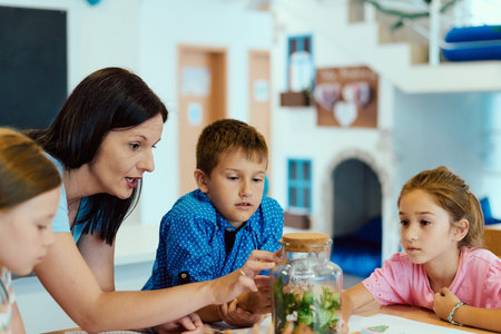 Teacher and children exploring a classroom terrarium during a hands-on science learning activityの写真素材