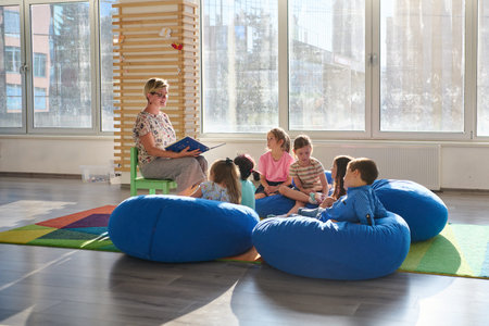 Teacher reading a story to a group of children during circle time in a bright classroomの写真素材