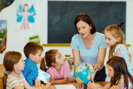 Teacher shows globe to a group of elementary students in a classroom geography lessonの写真素材