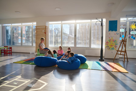 Teacher reading to children on bean bags during storytime in a bright preschool classroomの写真素材