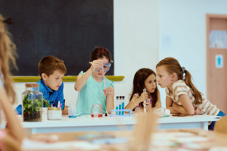 Children conducting a science experiment together in a classroom with test tubes and safety gogglesの写真素材