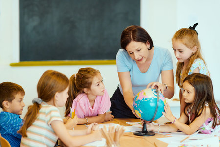 Teacher leading elementary students around a globe during a hands-on classroom geography lessonの写真素材