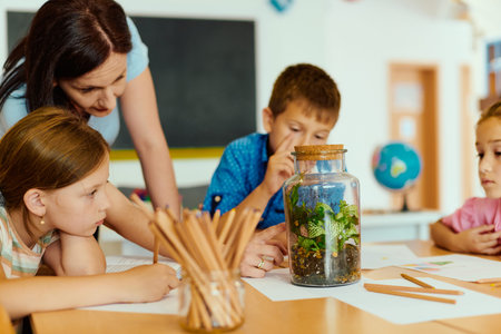 Teacher showing class a terrarium while elementary students observe and learn in classroom activityの写真素材