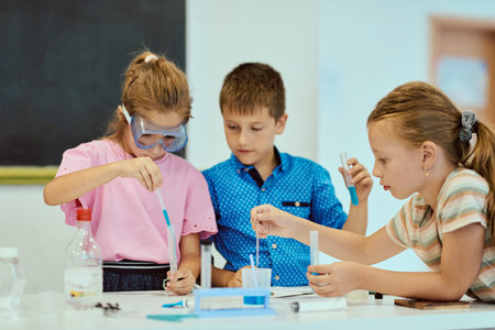 Children doing a hands-on science experiment at school with test tubes and safety gogglesの写真素材