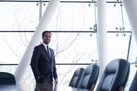 Middle Eastern businessman in a modern corporate boardroom smiling during a professional business meeting