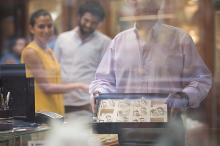 Middle Eastern couple buying a wedding ring with friends and family in a jewelry store