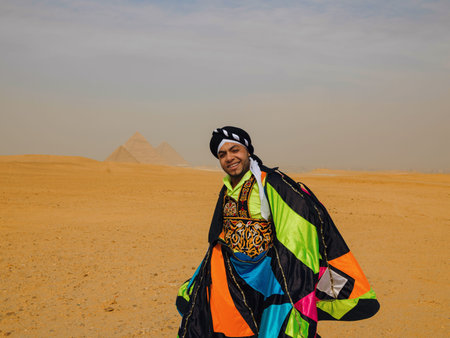 Joyful Egyptian tanoura dancer in vibrant multicolor folk costume smiling proudly in the desert before the Giza pyramids ideal for cultural festival