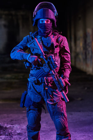 Armed Tactical Soldier In Night Urban Environment Holding Rifle With Helmet And Body Armor
