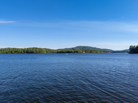 Small boat on Canada lake view with forest and mountains at edge of lake in summerの写真素材