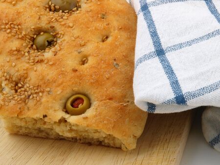 Olive bread on a table, with a knife. Close up on white backgroundの写真素材