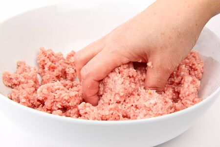 Hand working with minced meat. Close up on white backgroundの写真素材