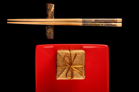 Chinese dinner table. Black table. red plate, a gift iis placed on the plateの写真素材
