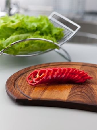 Sliced red peppers on a cutting board with green lettuce on the backgroundの写真素材
