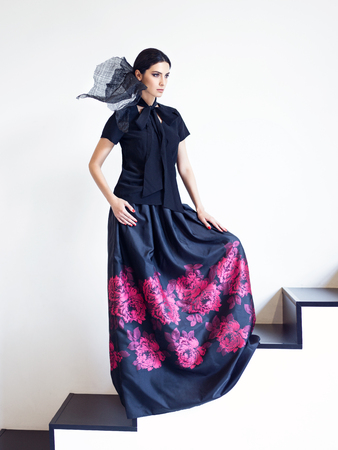 Woman in black shirt and long skirt with floral print posing on stairs. Fashion style portraitの写真素材