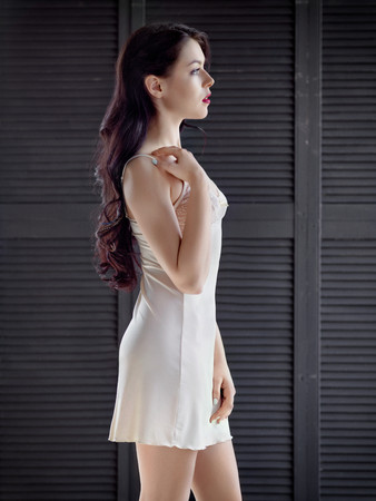Woman in a silk nightie on gray backgroundの写真素材