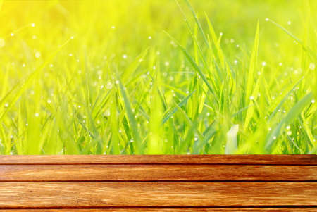 wooden table on nature field of green grass texture in the morning, spring and summer backgroundの写真素材