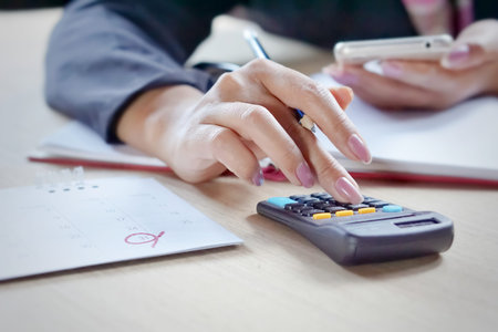 close view of a buisiness woman hand calculating her monthlty expenses during tax season.