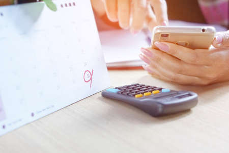 a business woman hand calculating her yearly accounting report of income and expenses with her smart phoneの写真素材