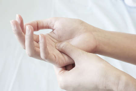 closeup of a woman pressing the middle of her palm with her thumb to relieve pain due to a tendinitis caused by an excessive use of computer, laptop, phone.の写真素材