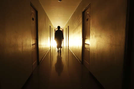 man silhouette walking through a lit corridor, which conveys the concepts of rebirth,evolution and achievementの写真素材