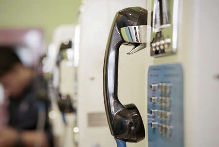 closeup of an old public payphone located in a department store with a blurred Asian person in the background.の写真素材