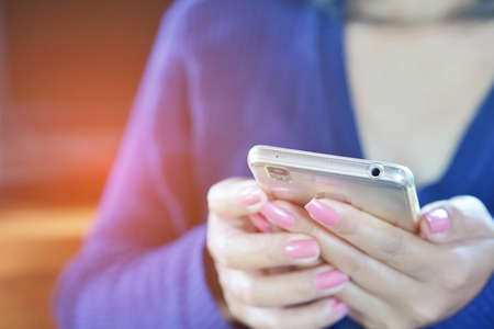 close up of a woman holding a smartphone in both hands to watch an entertaining movieの写真素材