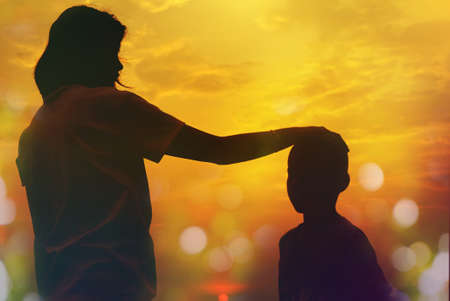 Mother and sun silhouettes at sunset with blur nature bokeh backgroundの写真素材