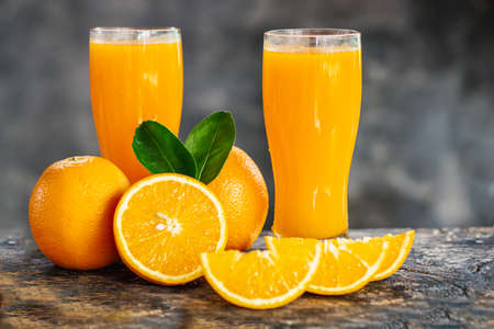 orange sliced and orange juice glasses with green leaf on wooden tableの写真素材