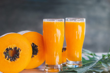 papaya slice and papaya juice on green leaf and wooden background, healthy and diet fruitの写真素材