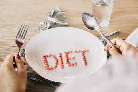 woman hand talking diet pills on dish ,unhealthy eating conceptの写真素材