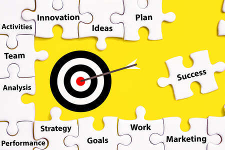 business plan and target concept with jigsaw  puzzle background and success signの写真素材