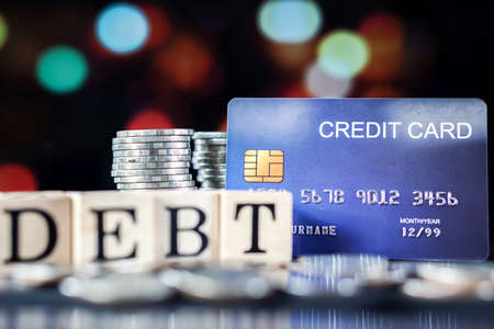 stack of coins, debt word and credit card, business and finance conceptの写真素材