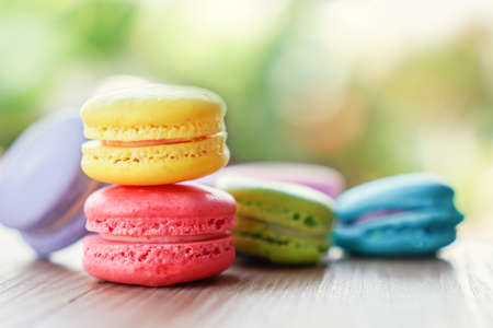 colorful french macarons on wooden table over nature backgroundの写真素材
