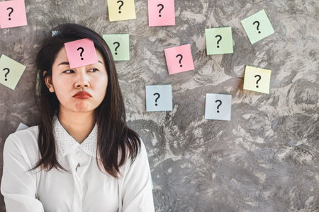 Asian woman worker with question mark on sticky note no idea at workplace