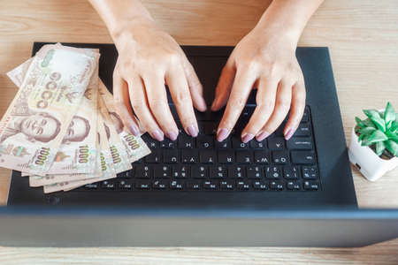 woman hand working and make money online from home with banknotes  on computer laptop during covid-19 pandemicの写真素材
