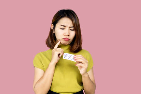 Asian woman forget and confuse to take contraceptive pill with wonder faceの写真素材