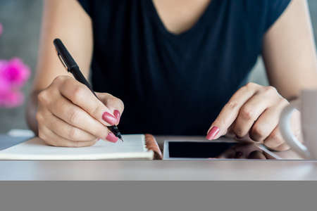 woman hand holding a pen and using smart phone for studying  online, e- learning from home concept