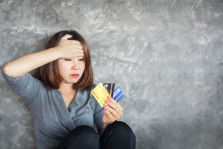 stressed Asian woman hand holding credit cards having problem with overspending and debt