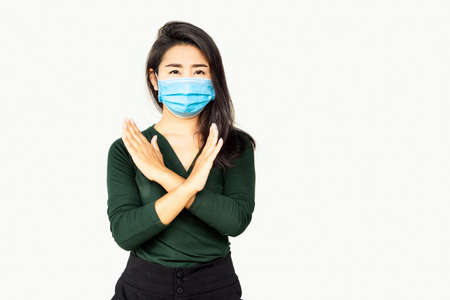 Asian woman wearing face mask  making stop sign gesture, refusing coronavirus disease standing over grey backgroundの写真素材