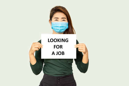 Asian business woman wearing protective mask hand holding a sign looking for a job ,Coronavirus or COVID-19 crisis conceptの写真素材