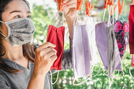 Asian woman hand washing protective fabric mask and hanging to dry outdoor, new normal during...